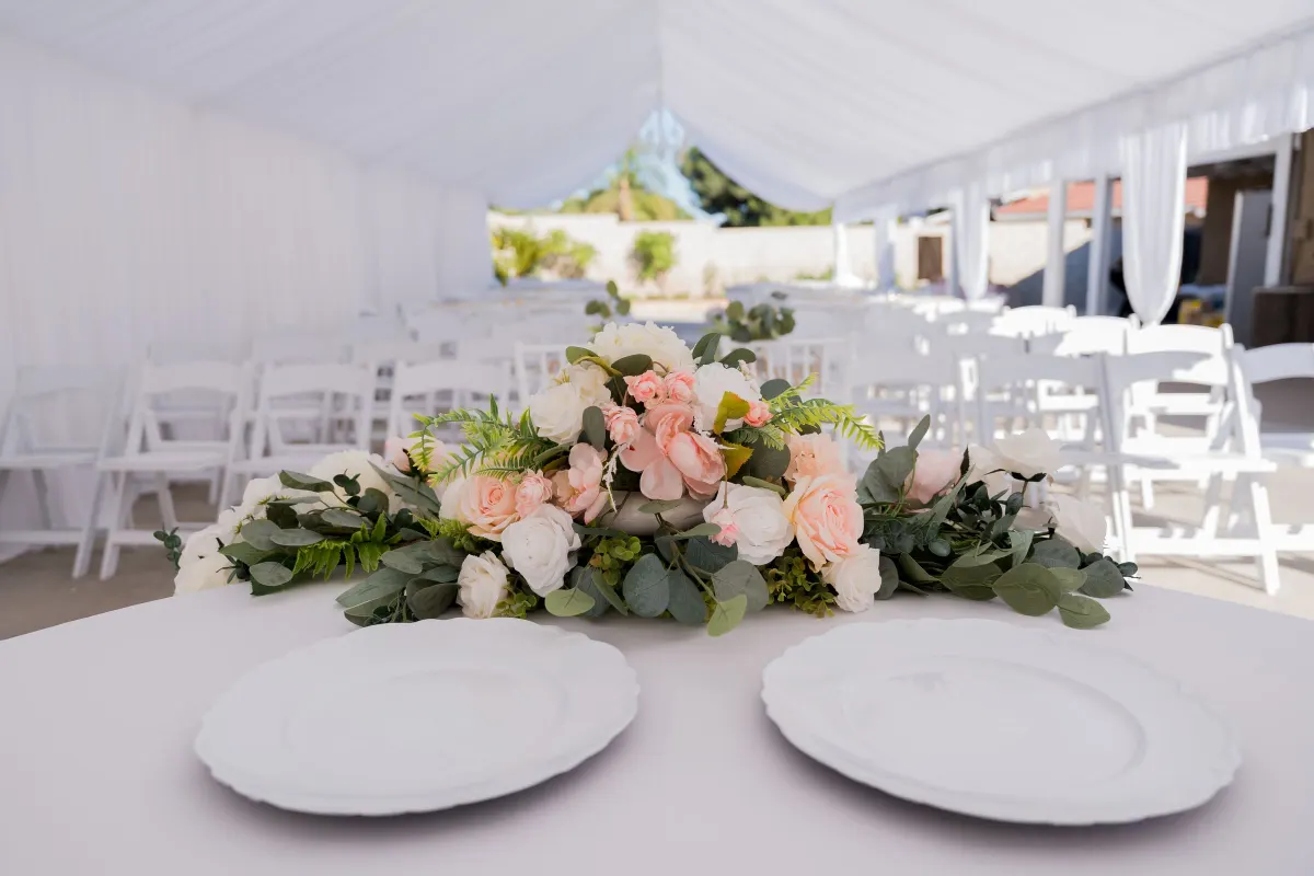 Mesa con centro floral dentro de una carpa blanca preparada para una boda