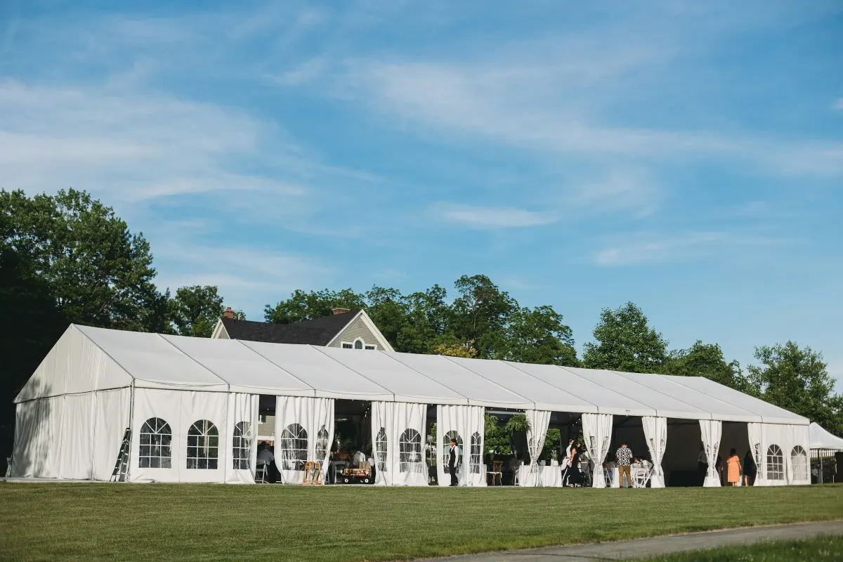 Carpa estructural blanca de gran longitud con ventanas, montada sobre césped