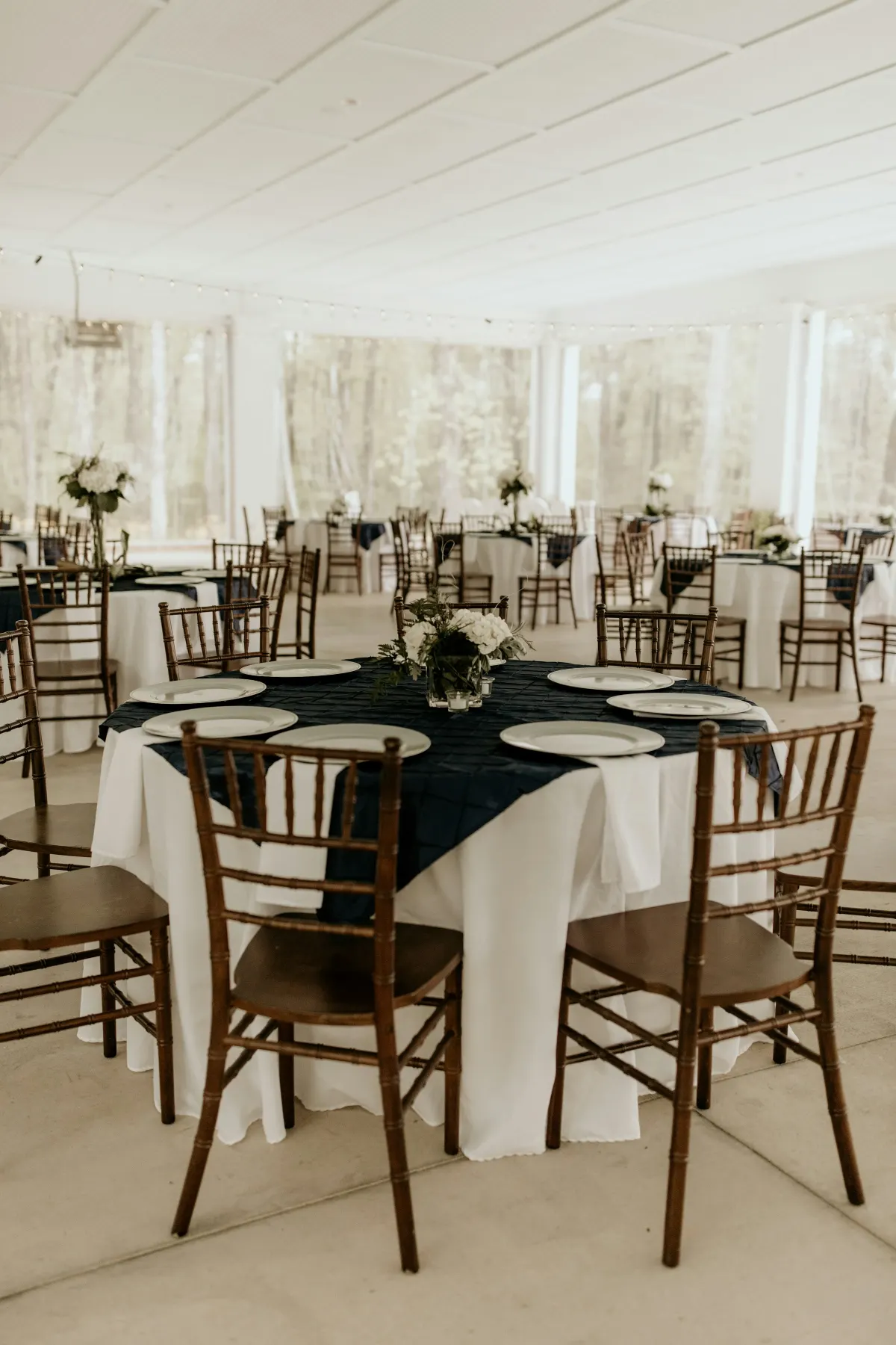 Interior luminoso de carpa con mesas redondas y sillas de madera