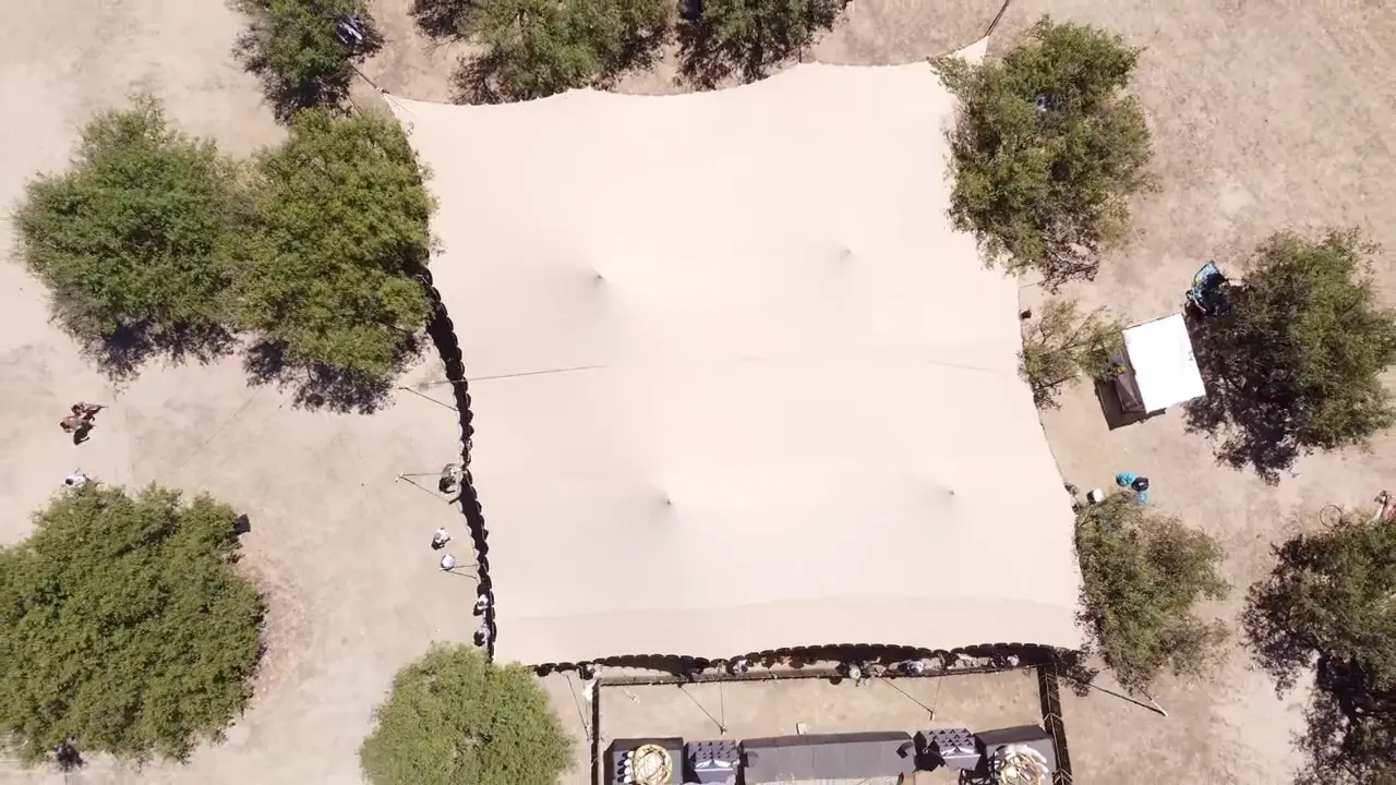 Vista aérea de una cubierta tensada color arena montada sobre terreno seco